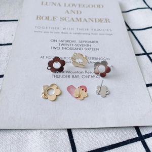 Close-up of DIY hollow floral stud earrings in gold and silver finish on a card