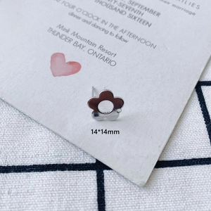 Macro detail of silver floral ear stud measuring 14x14mm on a decorative card