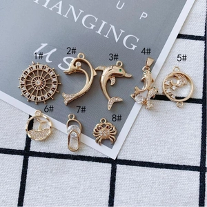Gold-plated marine charms with zirconia featuring dolphin, crab, and seahorse shapes