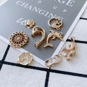 Collection of gold-plated copper charms with rhinestones in dolphin and crab shapes.
