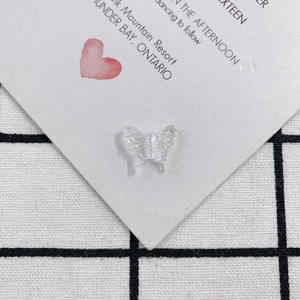 Close-up of translucent white acrylic butterfly pendants with pearlescent wing textures