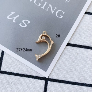 Detailed view of 27x24mm gold dolphin charm pendant with sparkling cubic zirconia stones