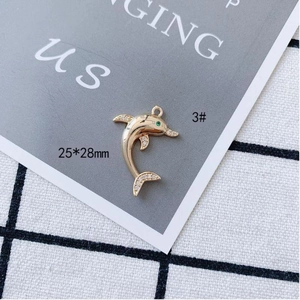 Macro shot of 25x28mm gold dolphin pendant with green eye and sparkling crystals