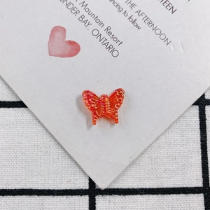 Macro shot of an orange translucent resin butterfly accessory with glitter for DIY jewelry
