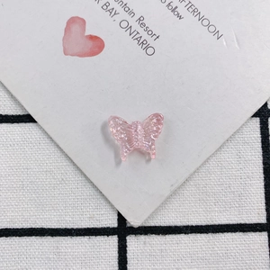 Detailed macro view of a translucent pink resin butterfly charm with subtle glitter shimmer