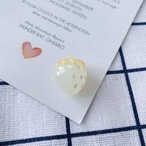Makroaufnahme von cremefarbenem Erdbeer-Anhänger mit Bernsteinblättern für DIY Schmuck