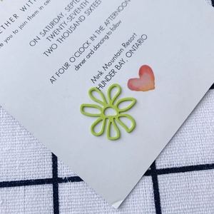 Macro shot of light green hollow flower pendant on white card and plaid cloth background