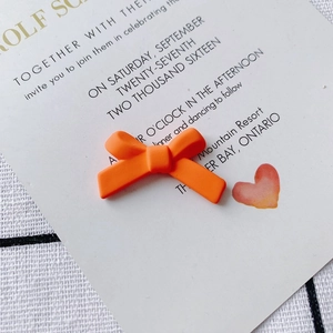 Macro-opname van mat oranje strikvormige harsbedels voor DIY-sieraden en haaraccessoires