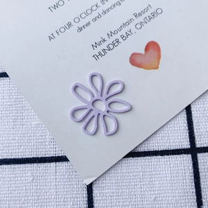 Macro shot of purple daisy-shaped cutout metal paperclip on decorative stationery card