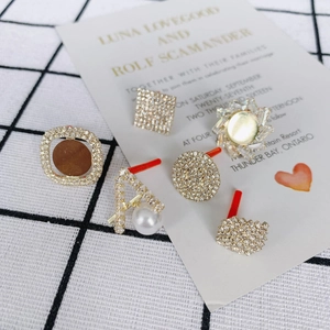 Vintage-Ohrringe in Gold mit Strass und Perlen auf einer weißen Displaykarte