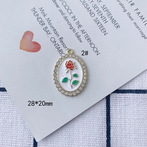Dettaglio pendente rosa 28x20mm con smalto rosso, foglie verdi e strass di cristallo
