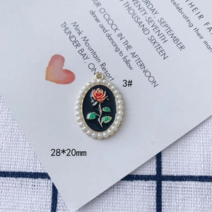 Dettaglio del ciondolo a rosa 28x20mm con smalto nero e perle finte bianche