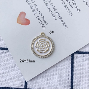 Dettaglio del ciondolo a rosa da 24x21mm in lega dorata con strass bianchi brillanti
