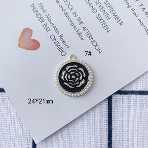 Vista macro del ciondolo rosa nera e oro 24x21mm con bordo di perle bianche tonde