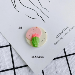 Detalle de un colgante redondo de arcilla polimérica de 34mm con cactus y flor rosada