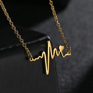 Collier minimaliste plaqué or 18k avec pendentif ECG battement de cœur sur fond noir élégant