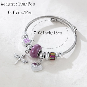 Detail of silver charm bracelet showing dragonfly pendant and heart love engraving