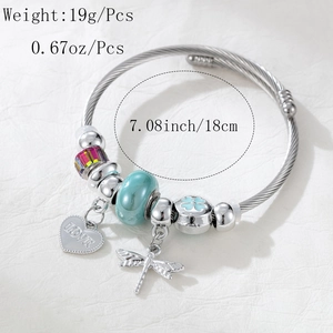 Detail view of dragonfly charm and love heart bead on beaded bracelet with 18cm size label