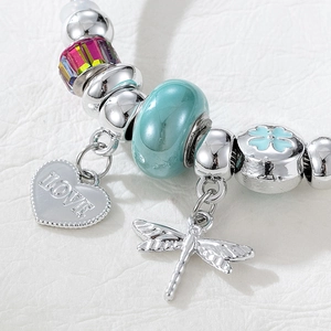 Detail of beaded charm bracelet with heart LOVE pendant, dragonfly, and blue clover bead