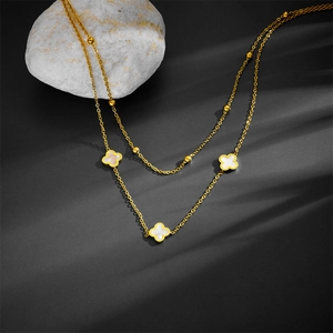 Close-up of double-layer gold necklace with white shell clover charms and metal beads