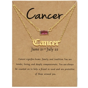 Nahaufnahme der doppellagigen goldenen Cancer-Kette mit Geburtsstein auf Sternzeichen-Karte