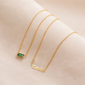 Détail du collier Taureau en or 18 carats avec pierre verte sur fond de soie blanche