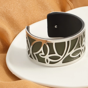 Detail of silver hollow butterfly cuff bracelet with green leather inlay on silk fabric