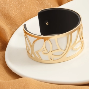 Macro detail of golden cutout butterfly cuff with premium white leather inlay