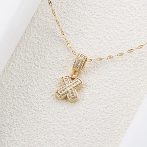 Dettaglio macro della collana con ciondolo lettera X dorata con zirconi cubici scintillanti