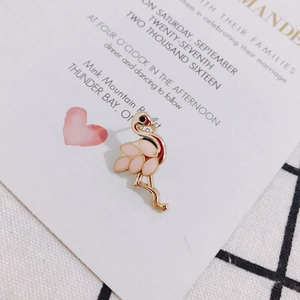 Nahaufnahme der rosa-goldenen Flamingo-Ohrringe auf einer weißen Einladungskarte