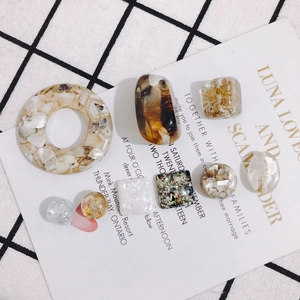 DIY hars sieraden accessoires met goudfolie en schelpen op een ruitjesachtergrond