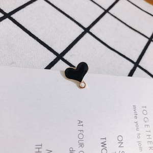Macro detail of heart-shaped black oil drip pendant with golden metal edge for DIY jewelry