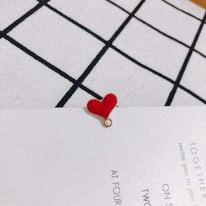 Macro detail of a red enamel heart charm with a gold metal loop for DIY jewelry making