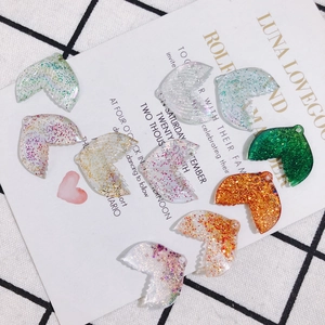 Detailed close-up of colorful glitter resin mermaid tail charms for DIY jewelry making
