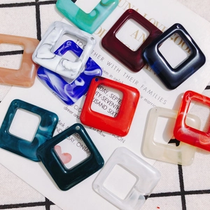 Close-up of geometric square acrylic resin charms with marble textures for DIY jewelry