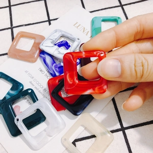 Handheld view of multi-color marble texture square acrylic charms for DIY earring making