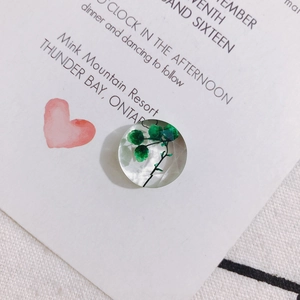 Detailed view of clear resin flower charm with green dried leaf for DIY jewelry making