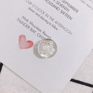 Detail of transparent resin flower charm with white beads on floral wedding card