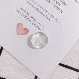 Macro shot of a faceted transparent resin charm with an embedded white dried flower petal