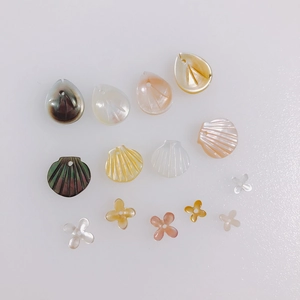 Detailed view of leaf and flower shell charms in white, pink, and yellow for DIY jewelry