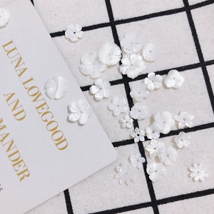 Detailed view of white carved shell flower beads for handmade jewelry and DIY hairpins