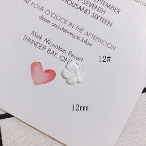 Close-up of 12mm white carved shell flower bead and red heart charm for DIY jewelry