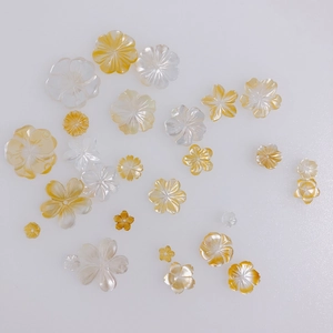 Dettaglio di fiori di conchiglia bianchi e ambra in varie dimensioni per gioielli fai-da-te