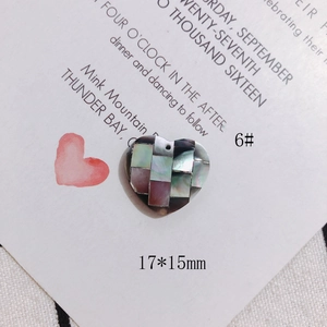 Macro detail of heart-shaped shell pendant with colorful mosaic inlay and top hole