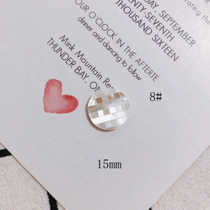 Close-up of 15mm shell button with checkered inlay and iridescent finish on white card