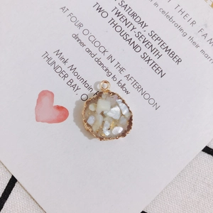 Dettaglio del ciondolo tondo in resina con inserti in conchiglia e bordo in metallo dorato