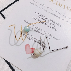 Close-up of spiral gold and silver conch pendants with decorative beads on a card