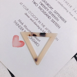 Détail du pendentif triangulaire en acétate avec motif écaille beige et trou de suspension
