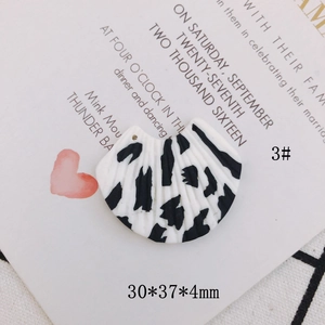 Macro detail of fan-shaped earring pendant with black spots and 30x37x4mm dimensions