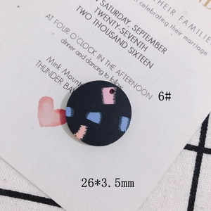 Detail eines 26mm runden schwarzen DIY-Anhängers mit rosa und blauen Farbmustern